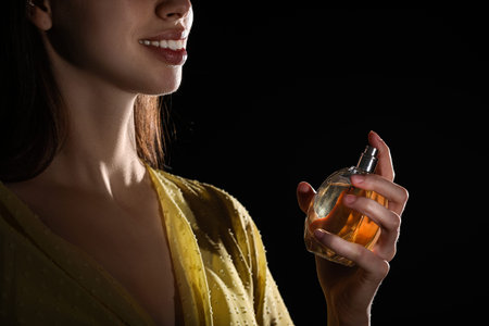 Beautiful woman with bottle of fresh perfume on black background