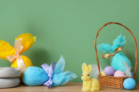 Easter decor with wicker basket and bunny on table near color wall