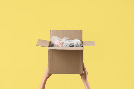 Woman with moving box on yellow background