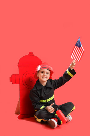 Cute little firefighter with USA flag and paper hydrant sitting on red background