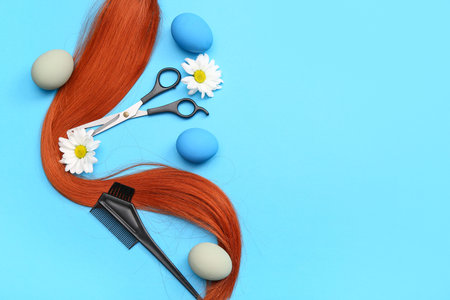 Hair strand with hairdressing accessories, daisies and Easter eggs on blue backgroundの写真素材