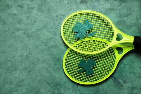 Tennis rackets with clovers on green grunge background. St. Patrick's Day celebration