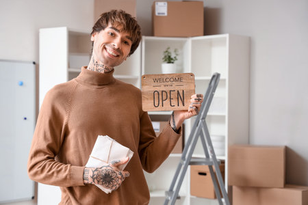 Young online store seller with envelopes and OPEN sign in warehouse