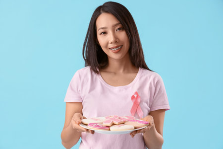 Young Asian woman with cookies on blue background. Breast cancer awareness conceptの写真素材