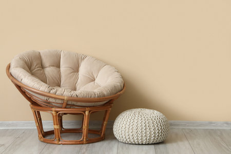 Stylish armchair and pouf near beige wallの写真素材