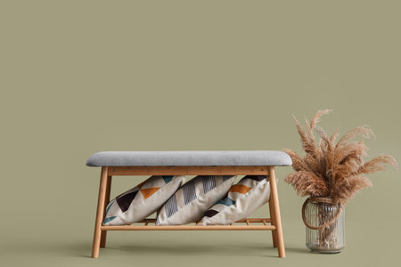 Soft bench with pillows and pampas grass in vase on green backgroundの写真素材