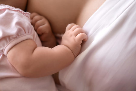 Young woman breastfeeding her baby at home, closeup