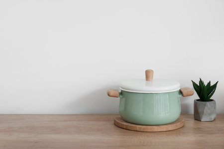 Green cooking pot and houseplant on wooden kitchen counter