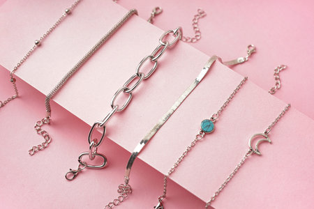 Many different stylish bracelets on pink background