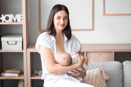 Young woman breastfeeding her baby at homeの写真素材