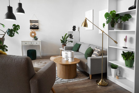 Interior of stylish living room with gray sofa, armchair and wooden coffee table at evening