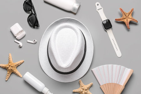 Composition with beach accessories, modern gadgets and starfishes on gray background