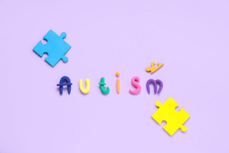 Word AUTISM made from plasticine with puzzle on lilac backgroundの写真素材