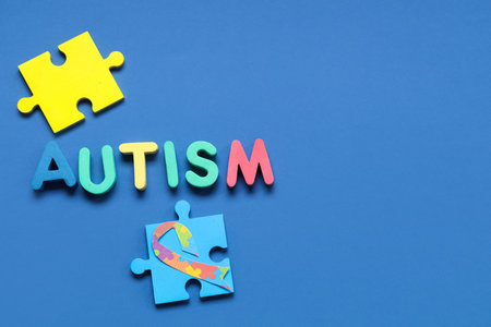 Word AUTISM and puzzle on blue background. concept of autistic disorder