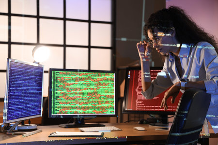 Female African-American programmer working near table in office at night