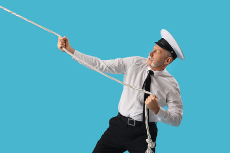 Mature sailor pulling rope on blue background