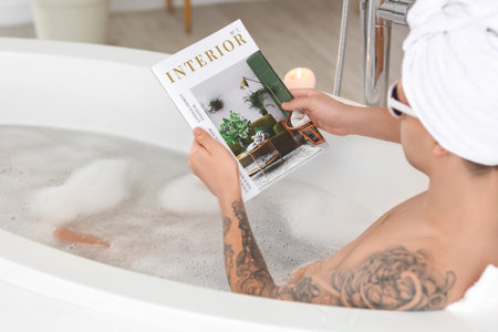 Young man with magazine taking bath at home, closeup