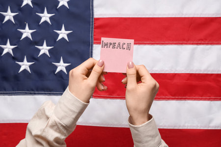 Woman holding piece of paper with the word IMPEACH against USA flag