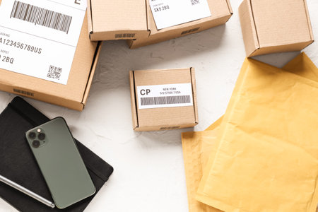 Cardboard packages, smartphone and envelopes on white table