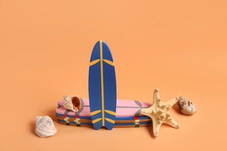 Different mini surfboards, stone, seashells and starfish on orange backgroundの写真素材