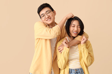 Young Asian friends hugging on beige backgroundの写真素材