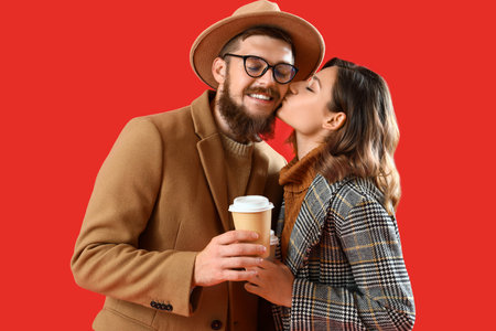 Happy couple in love with cups of coffee on red backgroundの写真素材