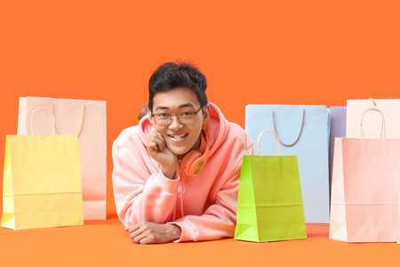 Young Asian man with shopping bags on red backgroundの写真素材