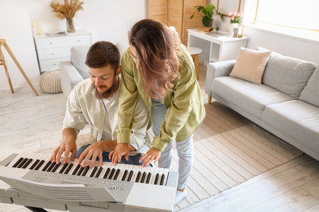 Happy couple in love playing synthesizer at homeの写真素材