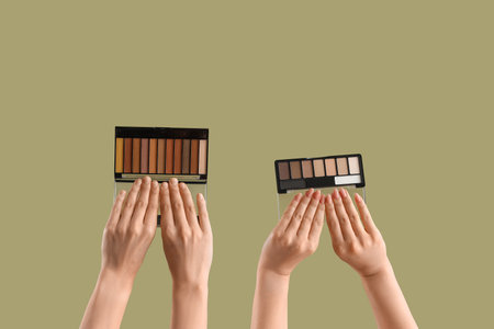 Women with eyeshadow palettes on green backgroundの写真素材