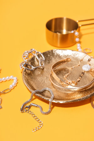 Plate and measuring cup with different beautiful bracelets on yellow backgroundの写真素材