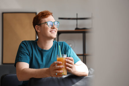 Young man with glass of juice at homeの写真素材