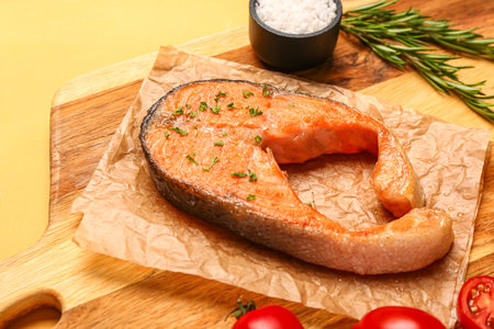Wooden board of tasty salmon steak on yellow backgroundの写真素材