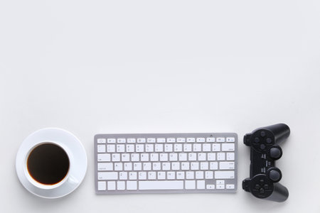Modern computer keyboard, cup of coffee and joystick on white backgroundの写真素材