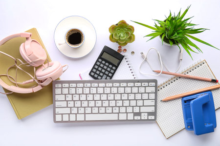 Composition with modern computer keyboard, headphones, cup of coffee and stationery on white...