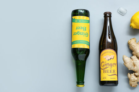 Composition with bottles of fresh ginger beer, lemon and ice cubes on gray backgroundの写真素材