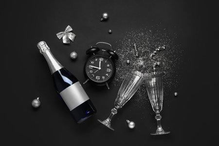 Composition with alarm clock, glasses, champagne and Christmas decorations on dark backgroundの写真素材