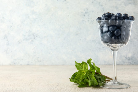 Glass with fresh blueberries and mint on white background