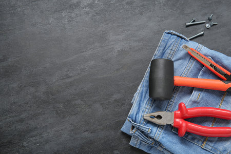 Jeans with different tools on black grunge background. Labor Day celebration