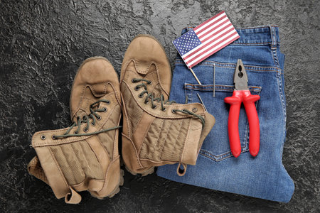 Pair of work boots, USA flag, jeans and pliers on black background. Labor Day celebrationの写真素材