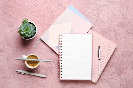 Notebooks with pens and cup of tasty coffee on pink backgroundの写真素材