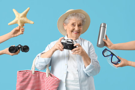 Senior female tourist and hands with travel accessories on blue backgroundの写真素材