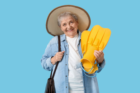 Senior female tourist with flippers on blue backgroundの写真素材