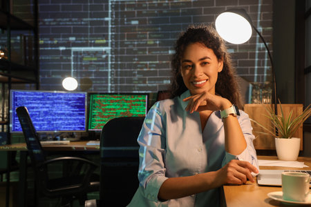 Female African-American programmer sitting in office at nightの写真素材