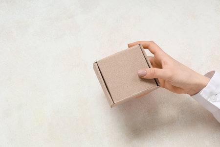 Woman holding cardboard box at white table, closeupの写真素材