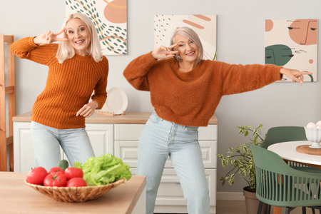 Mature female friends dancing in kitchenの写真素材