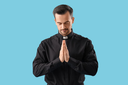 Portrait of male priest praying on blue backgroundの写真素材
