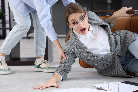 Young businesswoman fell down from chair getting help in office. Trauma conceptの写真素材