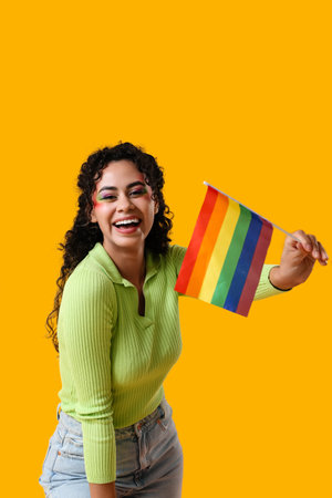 Happy African-American woman with rainbow flag on yellow background. LGBT conceptの写真素材
