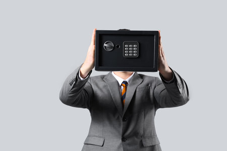 Young man with safe box on gray backgroundの写真素材