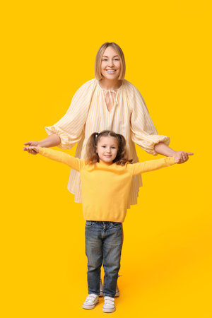 Mother playing with her child on yellow background. Mother's Dayの写真素材